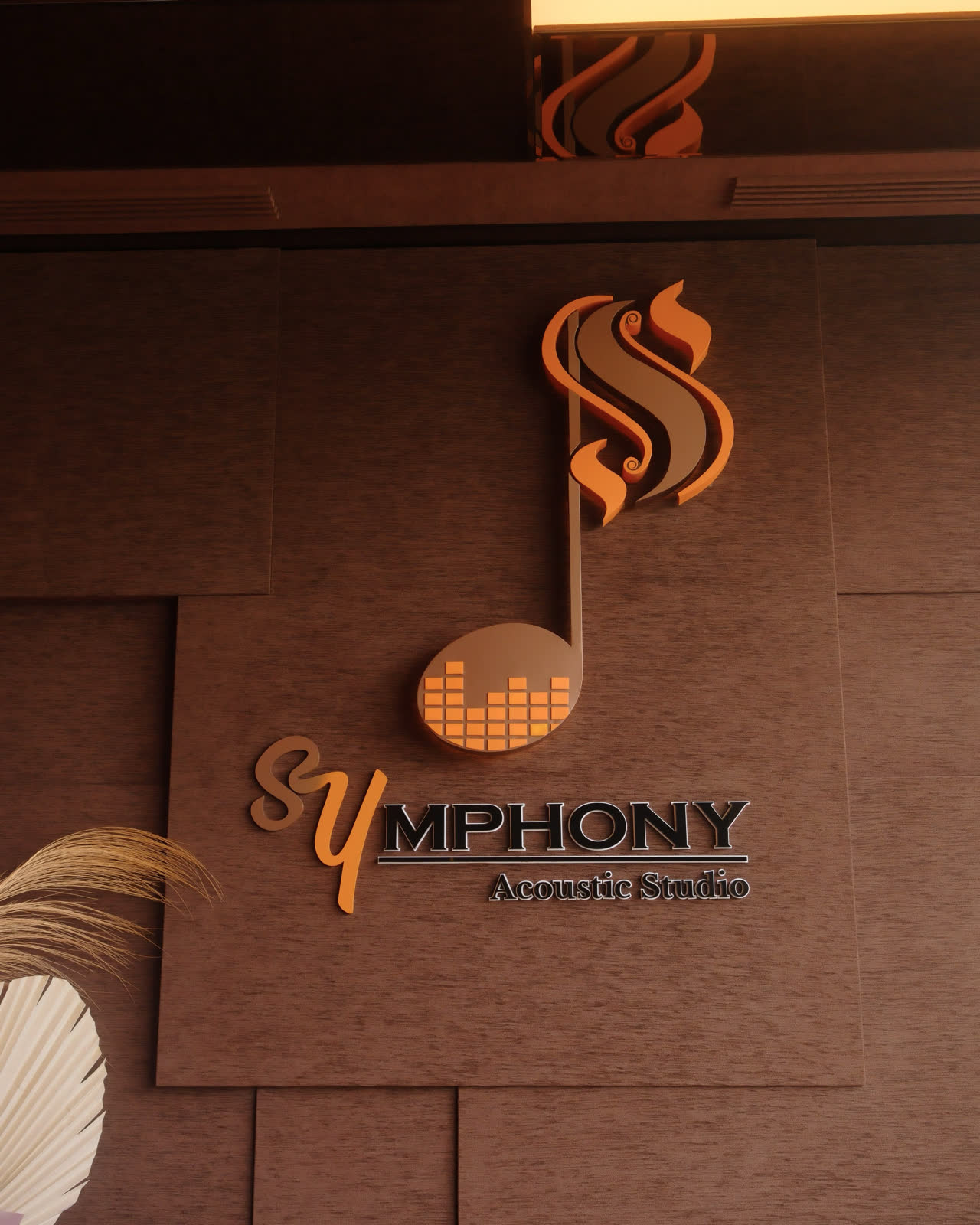 The Symphony Acoustic Studio mark, a quaver in walnut and burnt orange, mounted on the panelled wall of the studio.